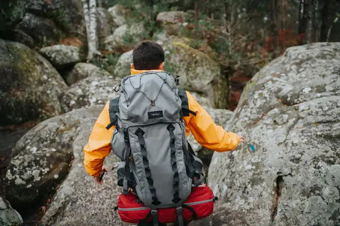a man with a backpack walking on a rocky trail